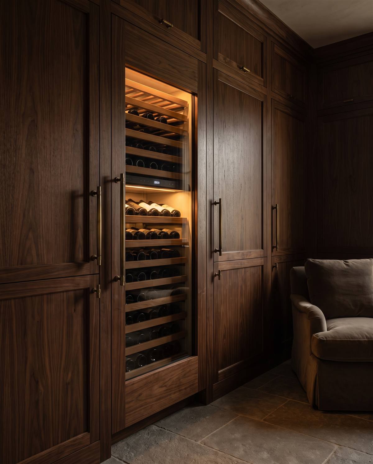 Sub-Zero wine column set into dark green millwork, amber interior glow